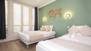 A hotel room with two beds, a world map wall decoration, and a window with a geometric pattern. - Daumesnil Grand - Two Bedroom Apartment, Sleeps 6 (Paris)