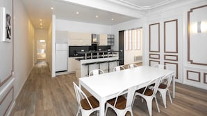 A modern kitchen with white cabinetry, a central island, and a dining area with a white table and chairs. - Daumesnil Grand - Two Bedroom Apartment, Sleeps 6 (Paris)