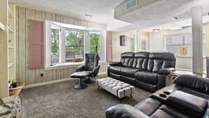 A cozy living room with a leather sofa, a recliner, and a window seat. - Making Lake Memories, Water Toys, Launch area /Dock/Slip, Fire pit, parking for group. (Linn Creek)