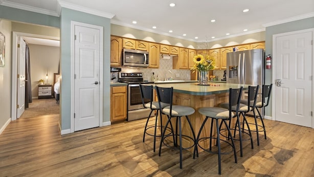 A modern kitchen with wooden cabinets, stainless steel appliances, and a central island with bar stools. - Making Lake Memories, Water Toys, Launch area /Dock/Slip, Fire pit, parking for group. (Linn Creek)