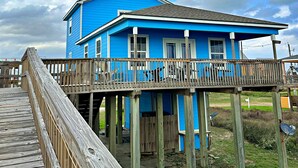 A blue house with a wooden deck and a picnic table. - The Aloha Beach your exquisite property that promises an extraordinary stay! (Surfside Beach)