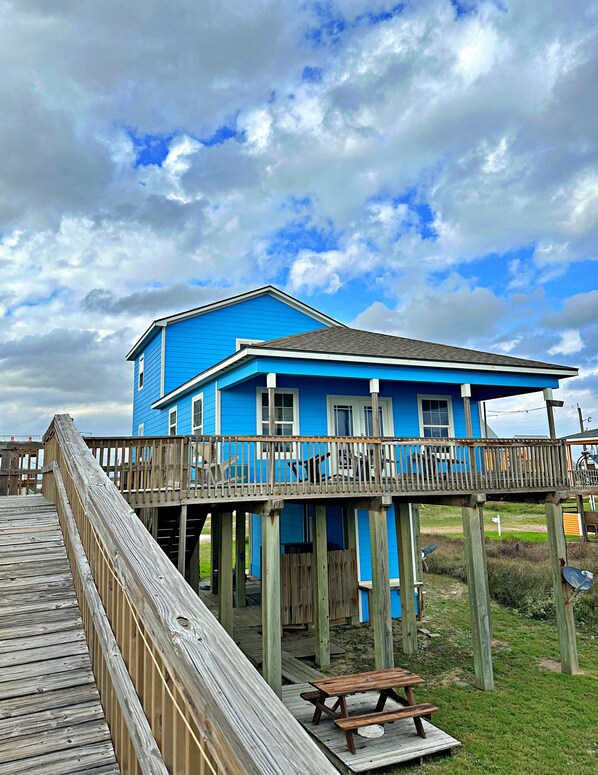 Uma casa azul com um deck de madeira e uma mesa de piquenique.