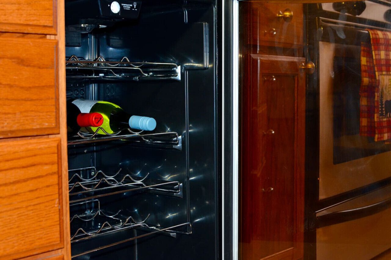Une cuisine équipée d’un réfrigérateur en acier inoxydable, de meubles de rangement en bois et d’un four à porte en verre.