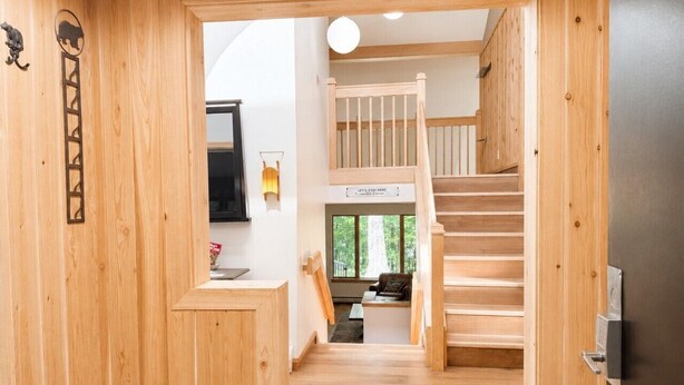 A wooden interior with a staircase, a kitchen area, and a seating space with a view. - SugarBear- Pool, AC, Sauna, Gym, Tennis! (Killington)