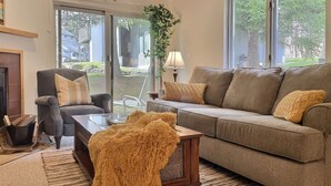 Un salon avec un canapé, un fauteuil et une table basse. On y trouve également une plante et une lampe.