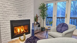 A living room with a fireplace, a sofa, a table, and a potted plant. - BearQuad- AC, Pool, Tennis, Close to Resort/Biking (Killington)