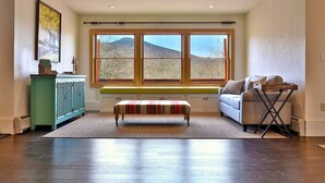 A cozy room with a bench, a sofa, and a window with a view of the outdoors. - Beartopia- Hot Tub, Views, 2 Primary Suites! (Killington)