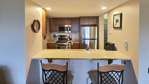 A compact kitchen with a central island, stainless steel appliances, and wooden cabinets. - Rockstar - Pool, Tennis, Fireplace, Pickleball (Killington)