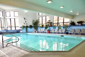 An indoor swimming pool with clear water, surrounded by windows and potted plants. - Rockstar - Pool, Tennis, Fireplace, Pickleball (Killington)