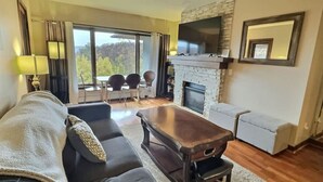 A cozy living room with a fireplace, a sofa, a coffee table, and a television. - Rockstar - Pool, Tennis, Fireplace, Pickleball (Killington)