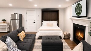 A modern bedroom with a bed, a sofa, a fireplace, and a television. - CubsCorner - Pool, Sauna, Gym, Close to Mountain! (Killington)