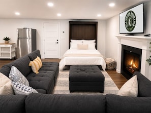 Une chambre moderne avec un lit, un canapé, une cheminée et un téléviseur.