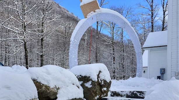 A snow-covered outdoor area with a large arch structure, rocks, and a building in the background. - CubsCorner - Pool, Sauna, Gym, Close to Mountain! (Killington)
