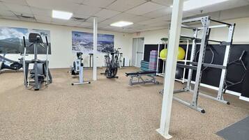A gym with various exercise equipment, including a bench press, dumbbells, and a squat rack.