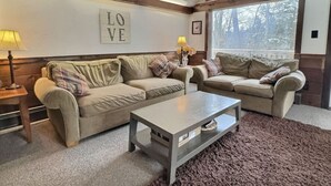 A living room with two beige sofas, a coffee table, and a 'LOVE' sign on the wall.