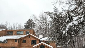 A wooden cabin with a sloped roof, surrounded by snow-covered trees.