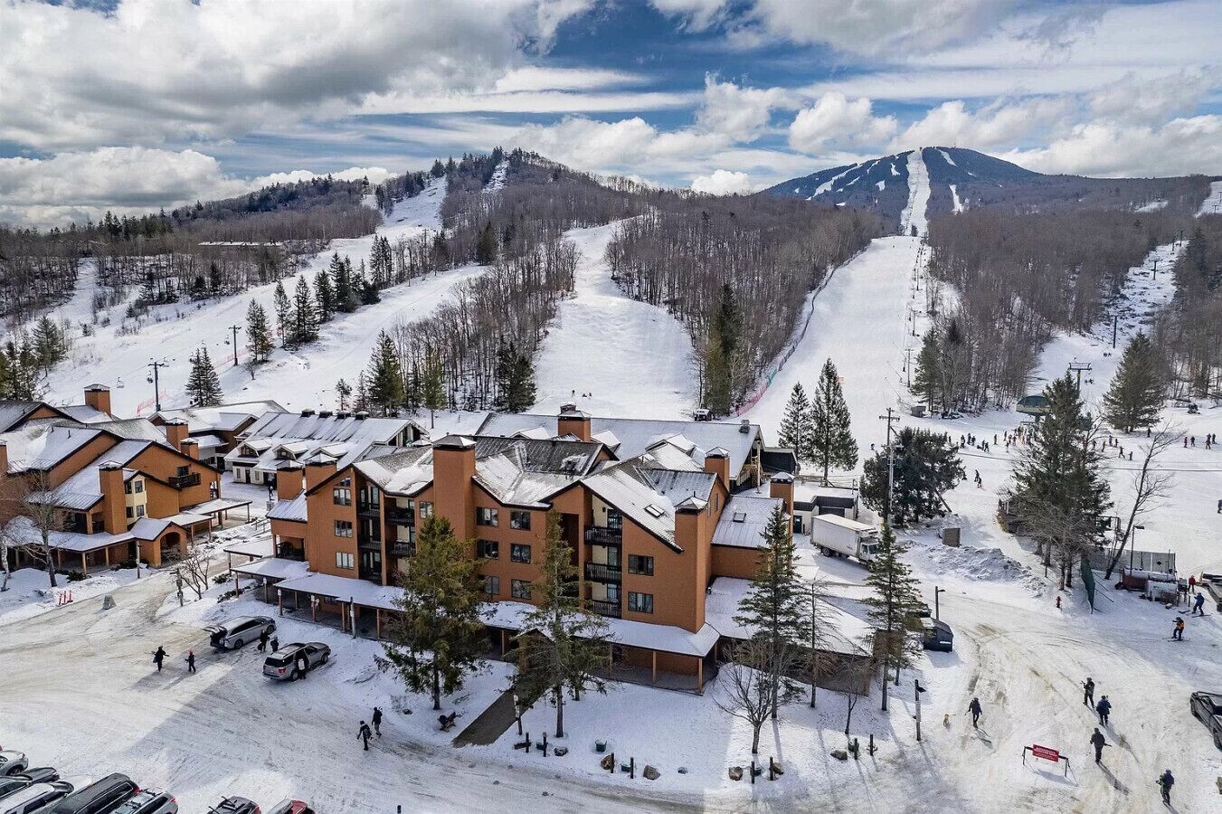 A ski resort with multiple buildings, a ski slope, and a mountain in the background.