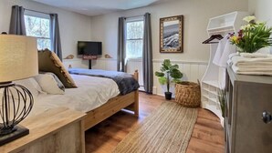 A bedroom with a wooden bed, a TV, a dresser, and a window with curtains. - DoubleDen Lower- AC, Fire place, Game Room (Killington)