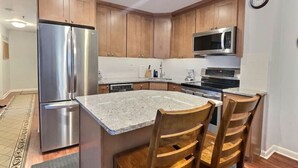 Uma cozinha moderna com eletrodomésticos de aço inoxidável, armários de madeira e bancada de granito.