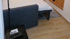 A modern bedroom with a bed, bedside table, lamp, TV, and a small plant.