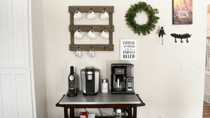 A coffee station with a coffee maker, a kettle, and a mug rack on a wall. - Large Kitchen, Hot tub, Game & Arcade Room (Hayden)
