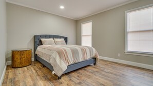 A bedroom with a bed, a round wooden side table, and a window with blinds. - Bailey Vacation Rental, 13 Mi to Downtown Wilson (Bailey)
