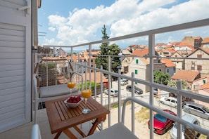 A balcony with a table, two glasses of orange juice, and a bowl of strawberries. - Deluxe Room located in Split (Split)