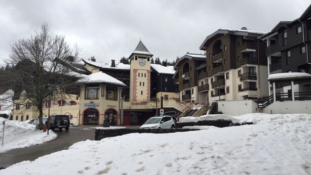 Un bâtiment enneigé, doté d’un clocher, d’un espace de stationnement et situé le long d’une rue également recouverte de neige.