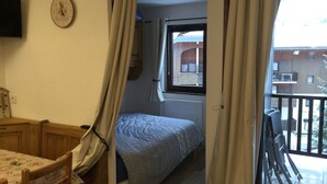 Une petite chambre à coucher avec un lit, une fenêtre et une vue sur l’extérieur.