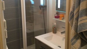 Une salle de bain avec une douche à parois de verre, un lavabo blanc et un miroir au-dessus.