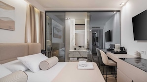 Ein modernes Hotelzimmer mit Bett, Schreibtisch, Stuhl und Fernseher.