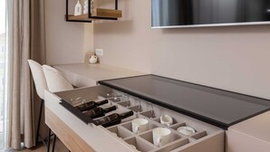 Habitació d'hotel moderna amb minibar integrat, televisió de pantalla plana i zona de seients amb una cadira.