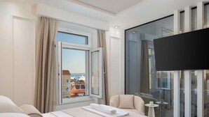A modern hotel room with a large bed, a TV, a balcony with a city view, and a small table. - Elegance Room in Split (Split)