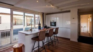 Una cocina moderna con una isla central, taburetes de bar y un amplio ventanal.