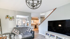 Un salon moderne avec un canapé gris, un téléviseur et un meuble en bois.