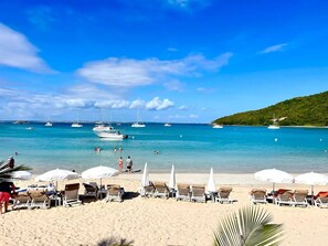 A beach with sun loungers and umbrellas, boats in the water, and a hilly landscape in the background. - Villa Norman: Unique 3 bedroom, 3 En-Suite Bathroom on 35 Acre Green Farmland (Saint Martin)
