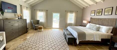 A bedroom with a bed, a dresser, a chair, a TV, and a ceiling fan.