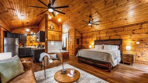 A log cabin interior with a kitchen, dining area, and a large bed.