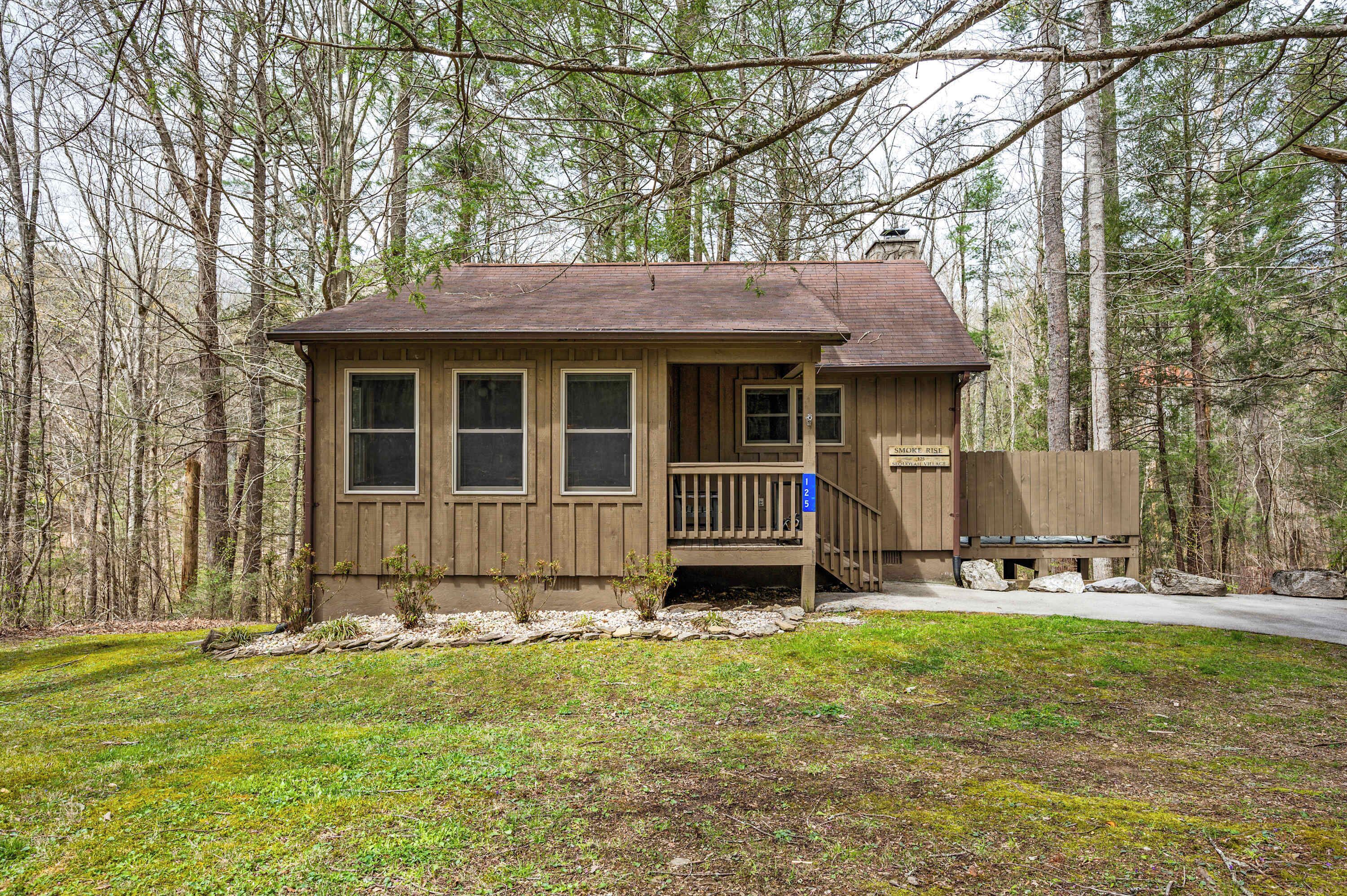 A small wooden cabin with a porch, a single window on each side, and a sign indicating it is a campground.