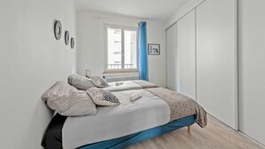 Um quarto com uma cama, uma janela com cortinas azuis e um radiador.