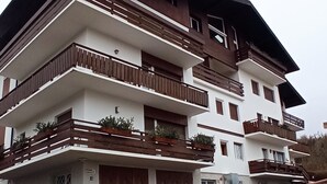 A multi-story building with balconies, a garage, and a log display. - Breathtaking Panorama  (Cortina d'Ampezzo)