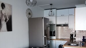 A modern kitchen with white cabinets, a built-in oven, and a sink. - Appartement Côte D'azur Accès Direct Plage (Théoule-sur-Mer)