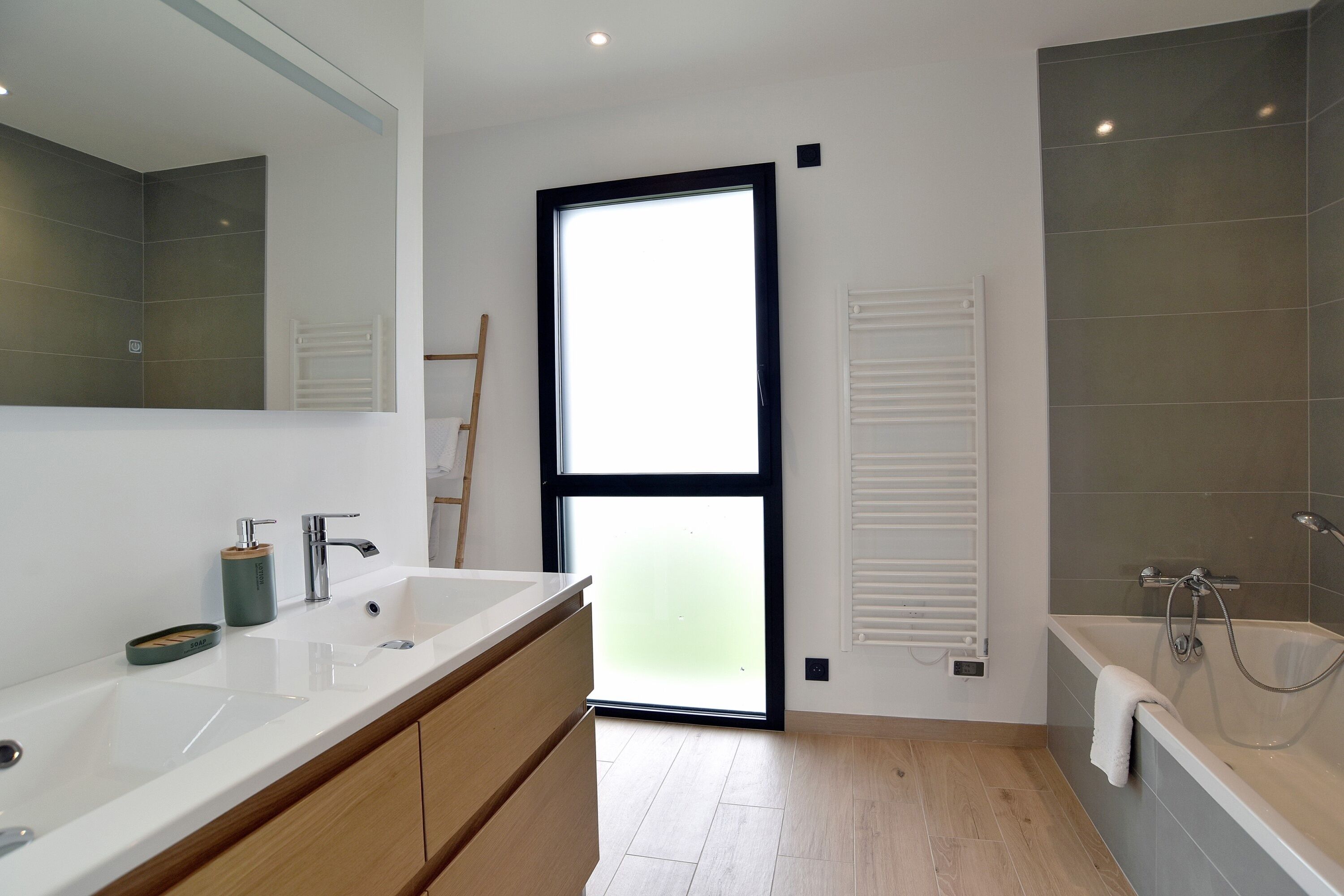 Ein modernes Badezimmer mit großem Fenster, einer Badewanne und einem Doppelwaschbecken.