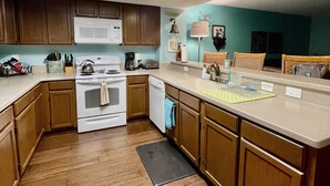 Una cocina moderna con armarios de madera, una estufa blanca, un microondas y un lavavajillas.