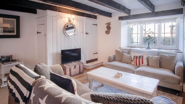 A cozy living room with a sofa set, a coffee table, and a television. - Milan Cottage - 2 Bedroom Cottage - Port Eynon (Swansea)