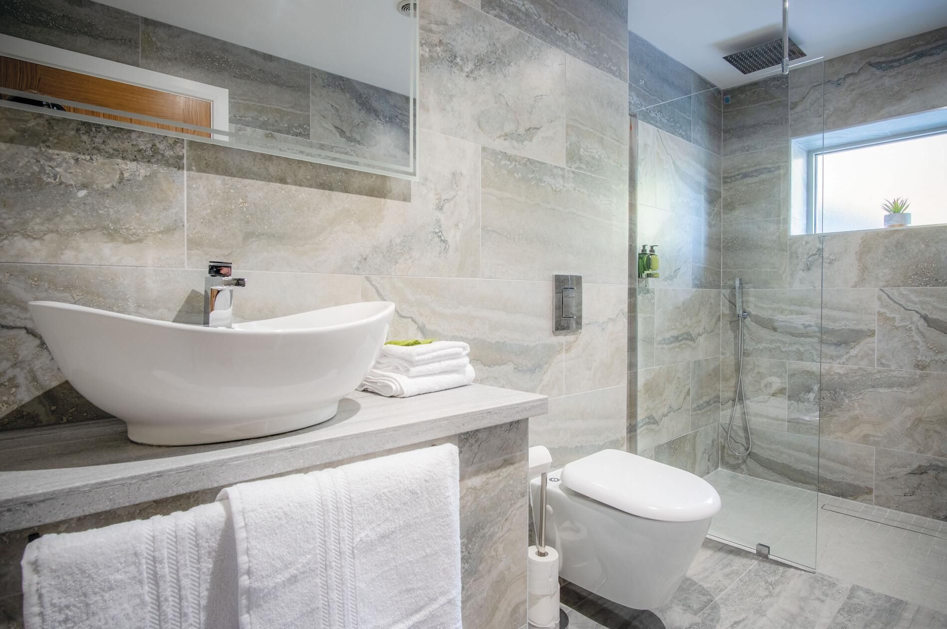 A modern bathroom with a freestanding bathtub, a toilet, and a glass-enclosed shower.