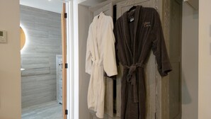 A bathroom with a wooden vanity, two bathrobes hanging on the wall, and a shower area visible through an open door. - Suite 14 - Sleeping Giant Hotel - Pen Y Cae Inn (Swansea Valley)