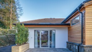 Una casa moderna con cimientos de piedra, fachada de madera y puerta de vidrio que da a un porche cubierto.