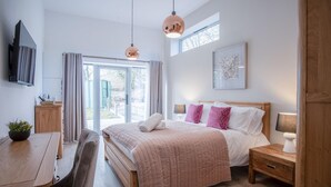 Een moderne slaapkamer met een groot bed, nachtkastjes, een bureau en een raam.