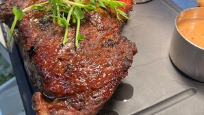Een steak met een garnering van groenten, vergezeld van friet en saus.